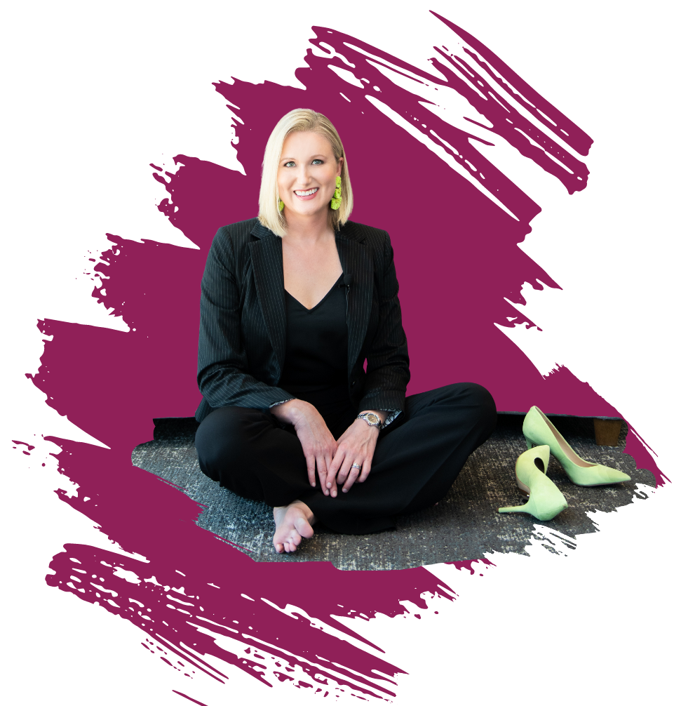 Katherine M. Sauer, wearing a black suit, seated cross-legged with her shoes kicked off 